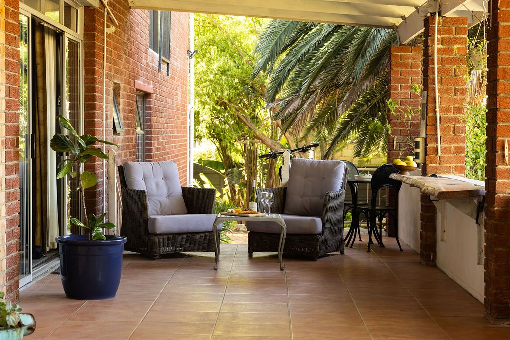 Covered patio with wicker lounge chairs and garden views