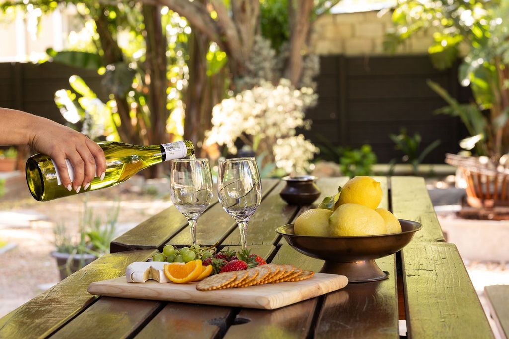 Pouring wine at a garden table set with fruit and cheese at Staymore