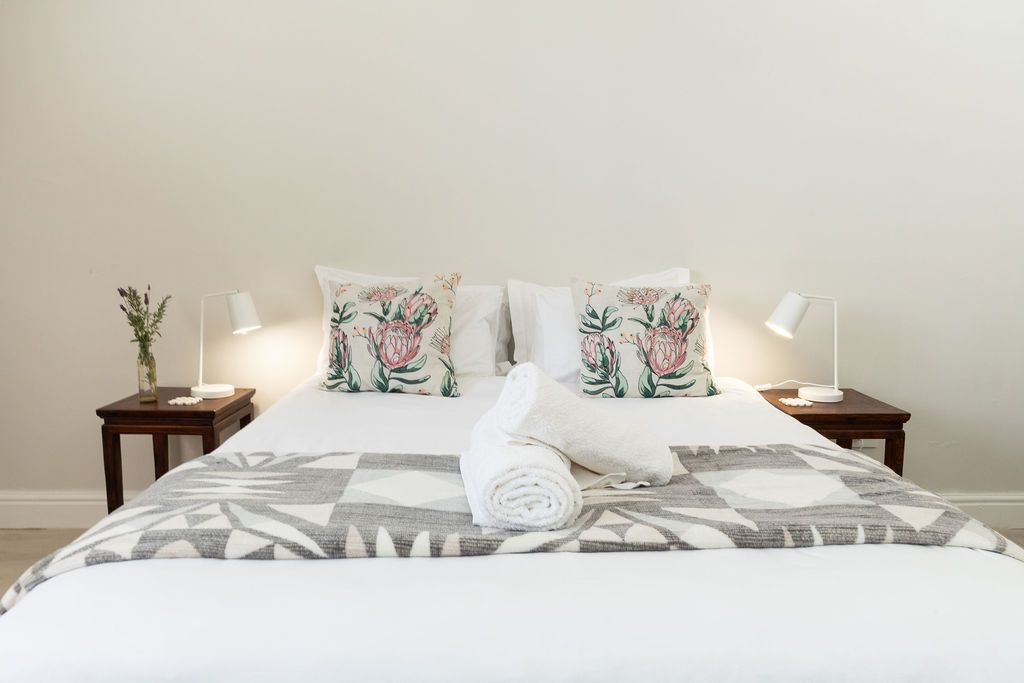 King bed with protea cushions and a patterned throw at Staymore